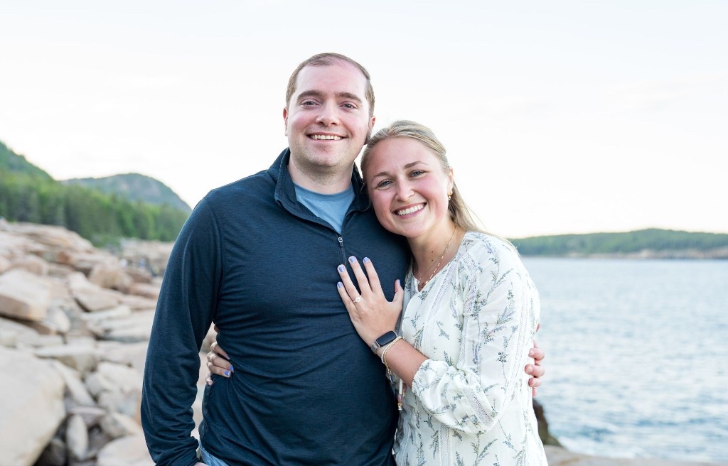Cecylia and Gregory smiling together on a rocky shoreline